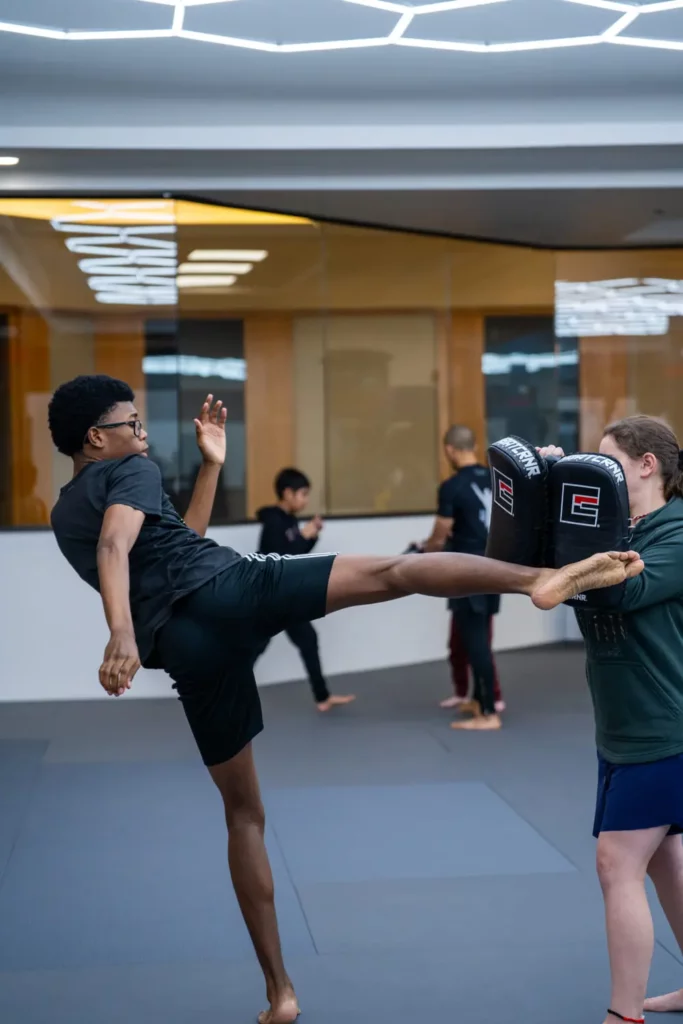 Student landing body kick on pads in beginner Muay Thai training