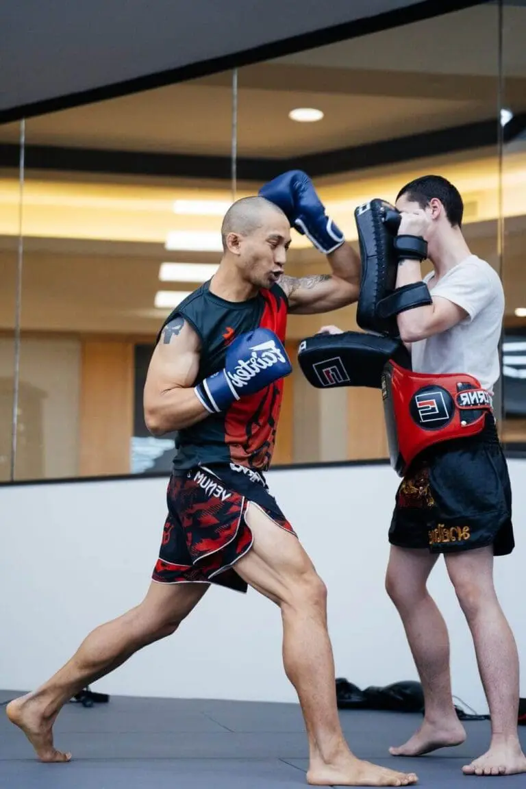 Fighter practicing elbow strikes on pads for Muay Thai techniques